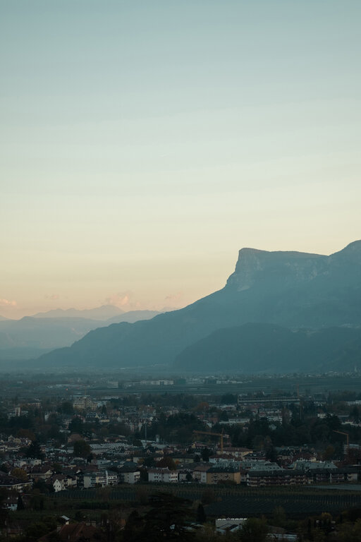 Blick über Meran mit den Bergen im Hintergrund bei Dämmerung