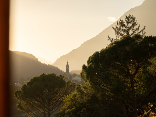Blick auf eine Dorfkirche im Tal mit sanftem Abendlicht